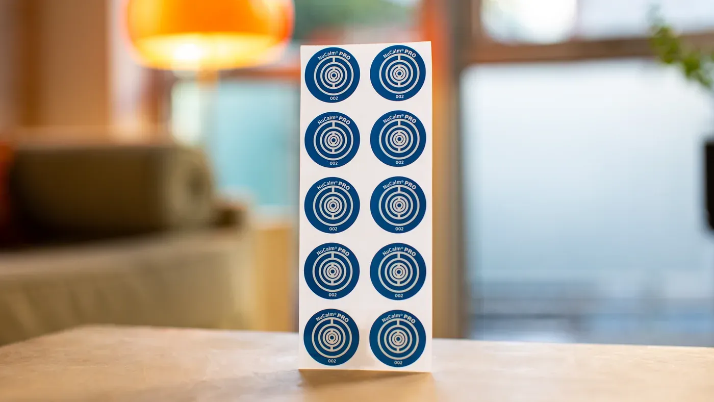 A sheet of NuCalm biosignal processing discs standing on a table