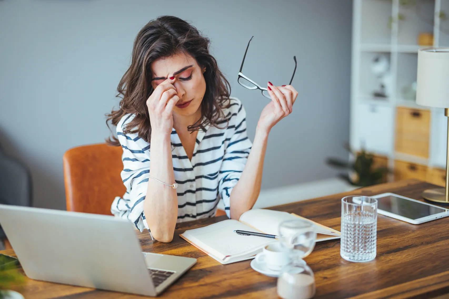 A woman sits at a desk working, her hand touching on her head.