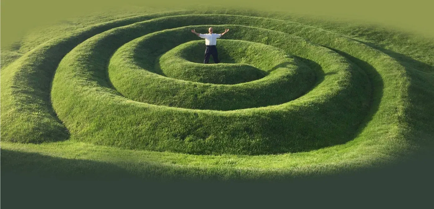 A spiral hedge maze in a green field