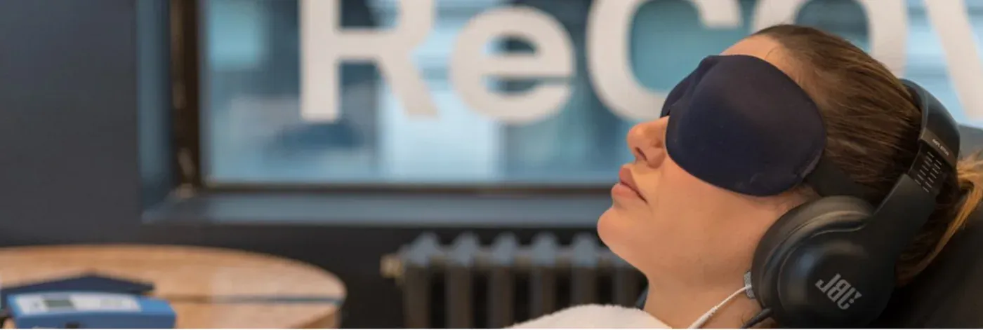 A woman relaxing in a NuCalm eye mask and headphones