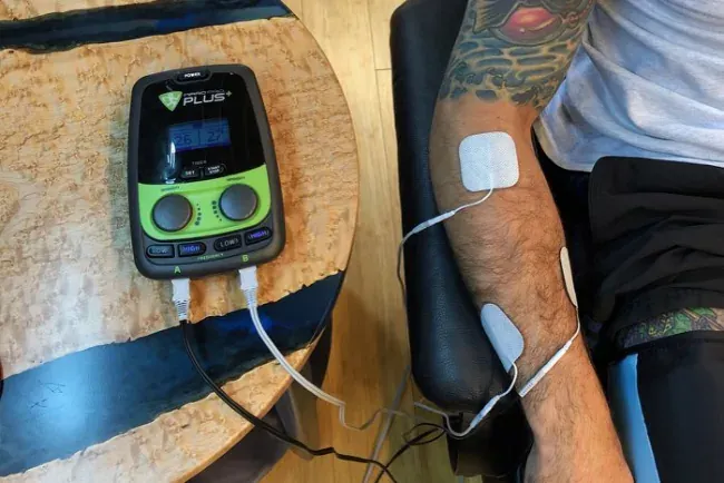 An electrical muscle stimulation unit with electrodes on a client's arm