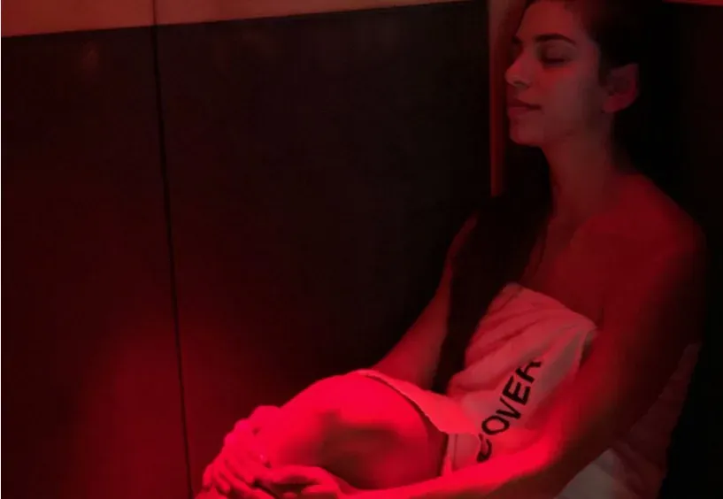 A woman in an infrared sauna bathed in red light
