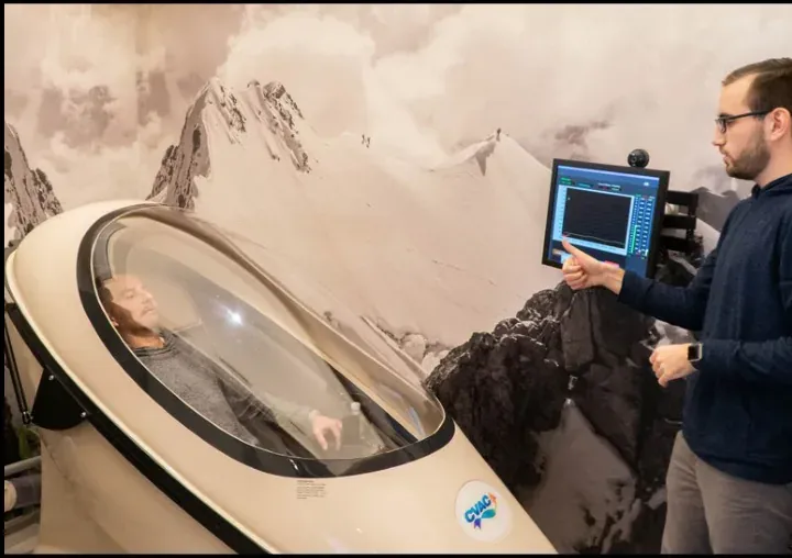 A client inside a CVAC pod while a staff member watches the control screen