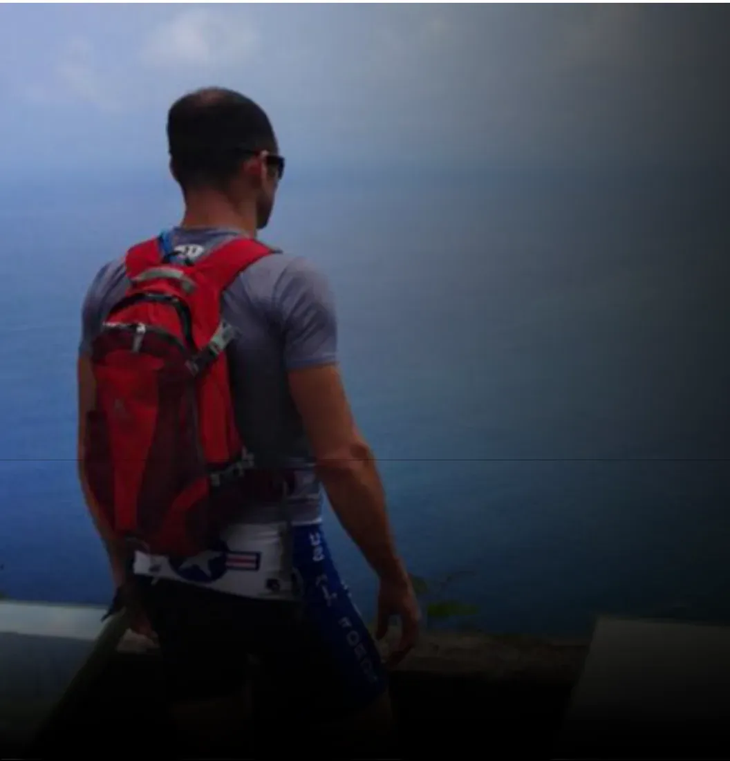 Ken with a hiking pack looking out over the water at dusk