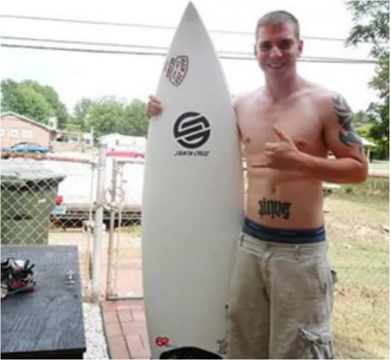 A young man holding a surfboard