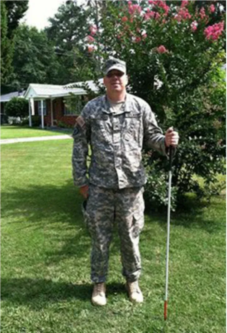 A soldier in uniform standing with a cane on a lawn