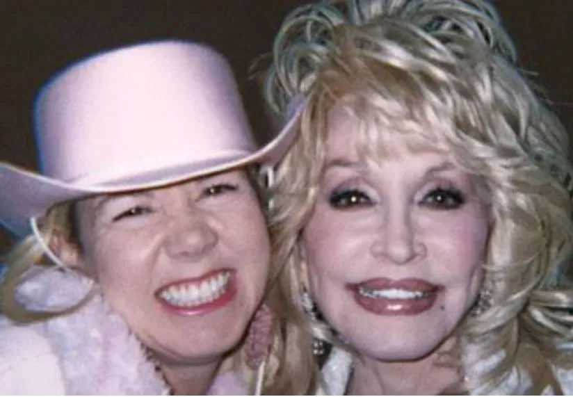 Two women in pink cowboy hats smiling together