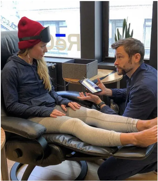 A client in compression boots talking with a RēCOVER staff member