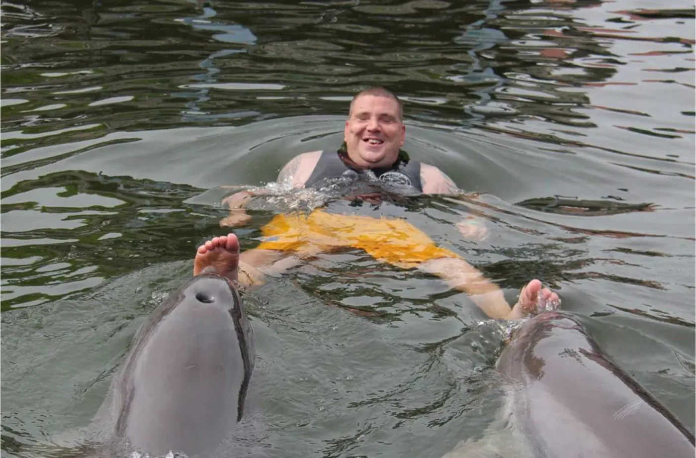Blake floating in the water with a dolphin