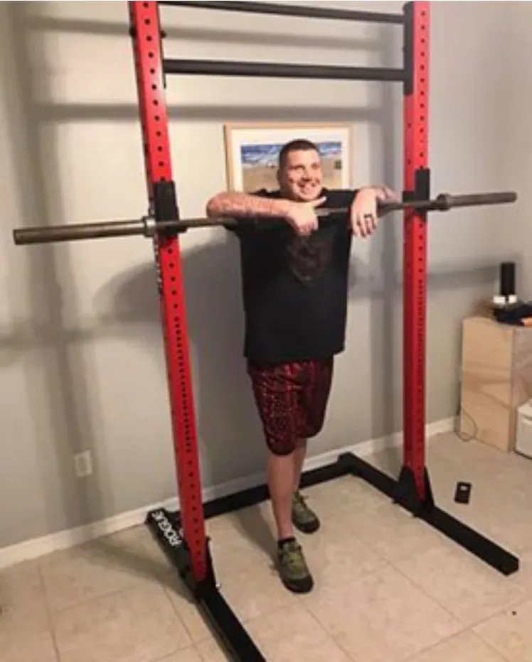 Blake standing in a squat rack in a home gym
