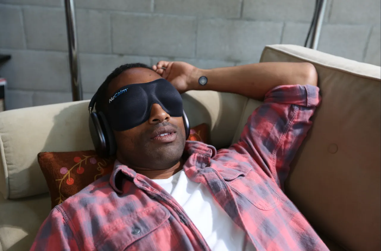 A man lying down with headphones and eyes closed, using NuCalm.