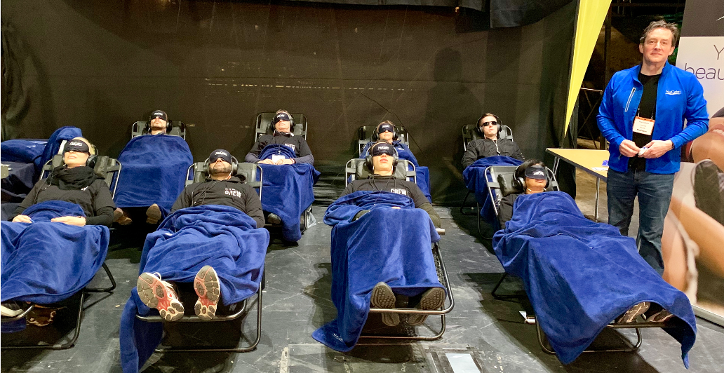 Poole stands next to rows of chairs filled with people using NuCalm, covered in blue sheets.