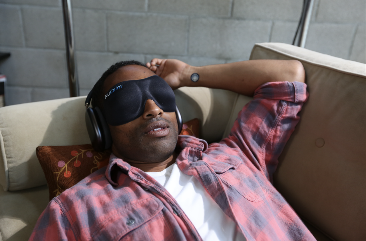 A man lying down with headphones and eyes closed, using NuCalm.