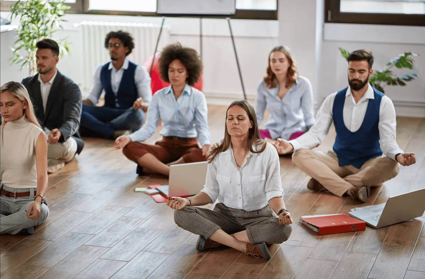 A group of professionals in Sukhasana yoga pose.